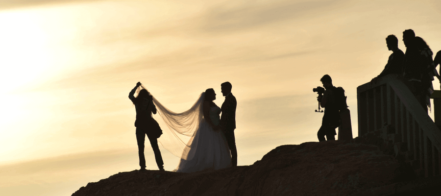 A couple being photographed at sunset on their wedding day