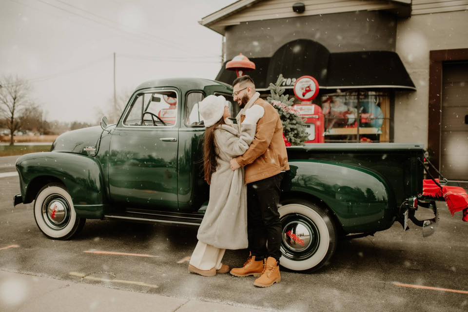 christmas holiday photoshoot of couple posing in front of the car